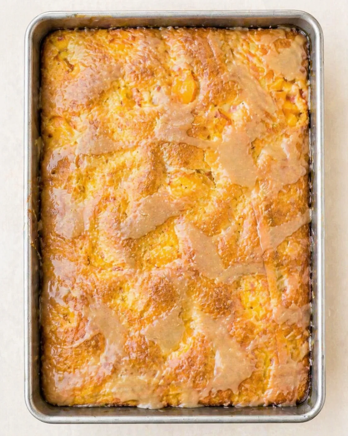Top-down view of a golden-brown glaze-topped cake baked in a metal 9x13 pan.