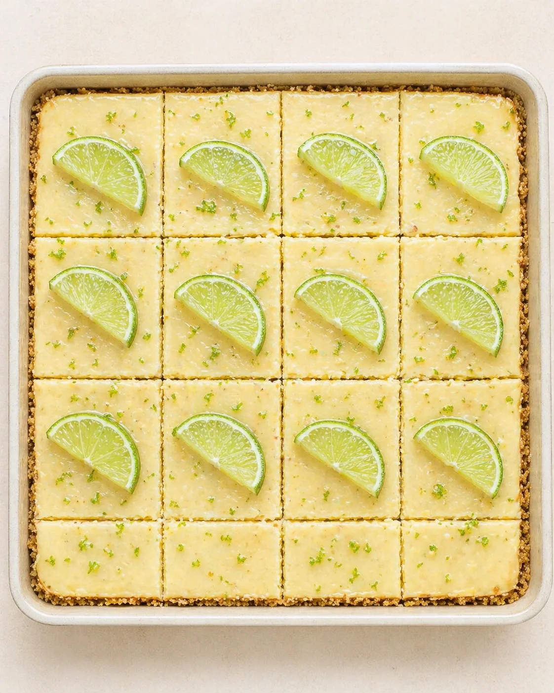 pan of lemon bars cut into 16 squares, each topped with a lime wedge