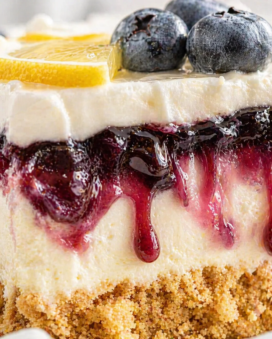 Close-up of a layered cheesecake with orange slices and blueberries on top