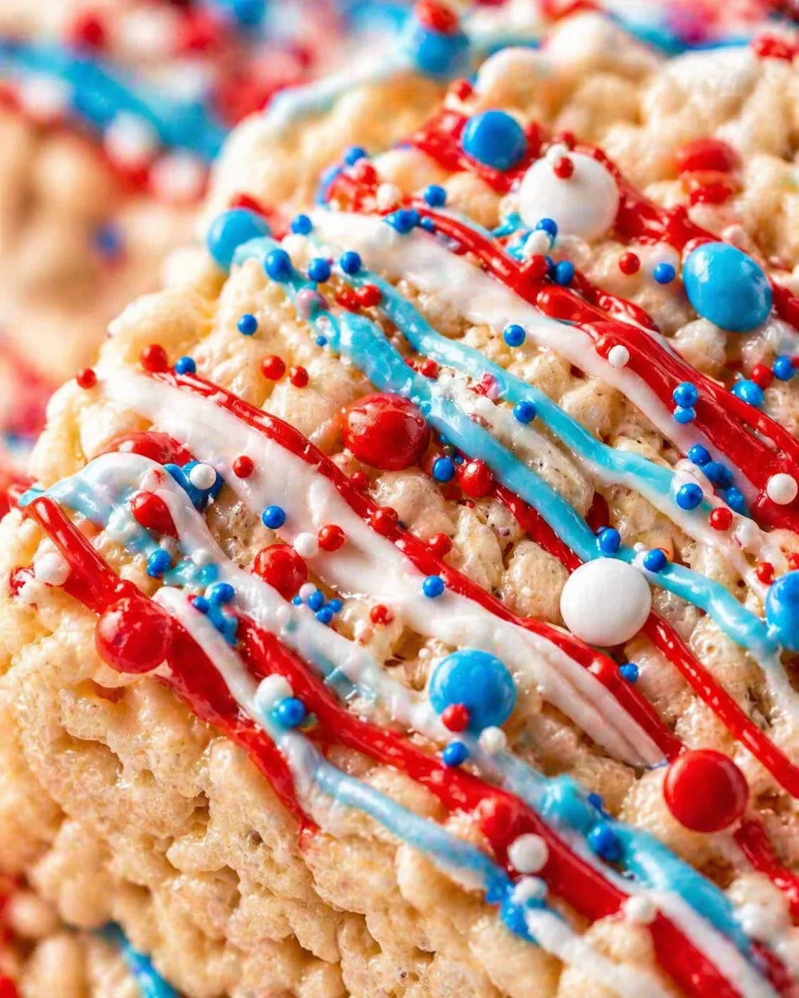 Close-up of a crumbly cookie topped with red, white, and blue icing and sprinkles.