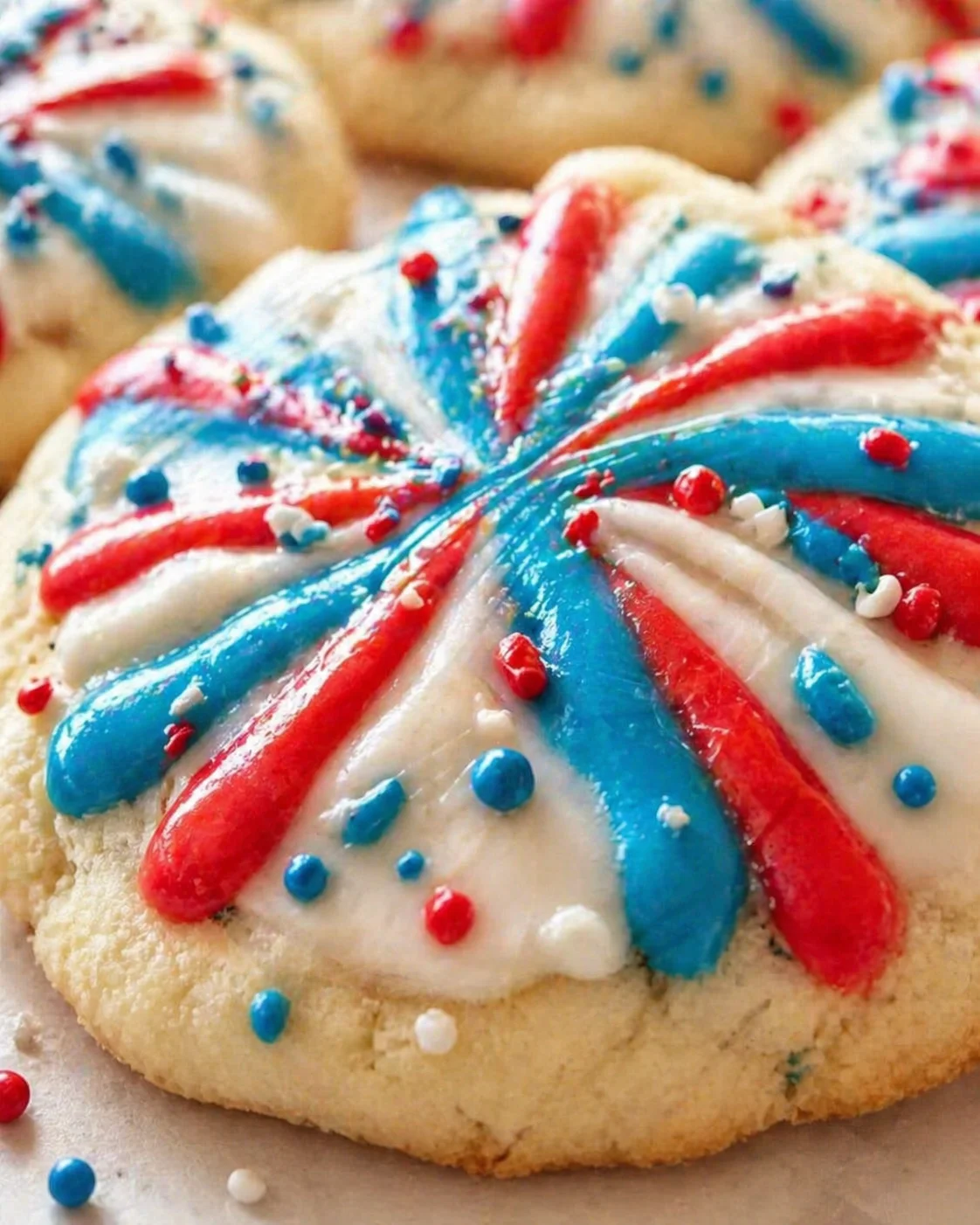 Close-up of a golden sugar cookie with red, white, and blue icing swirl and sprinkles