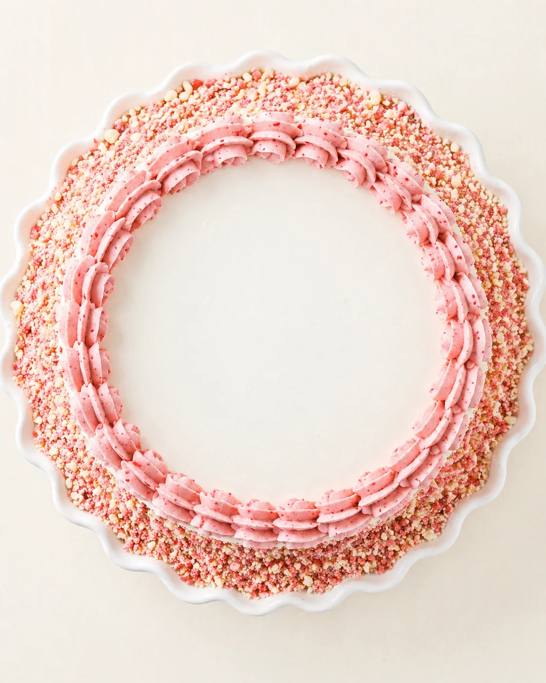 top-down view of a round cake with pink piping border and a crushed pink sugar crust