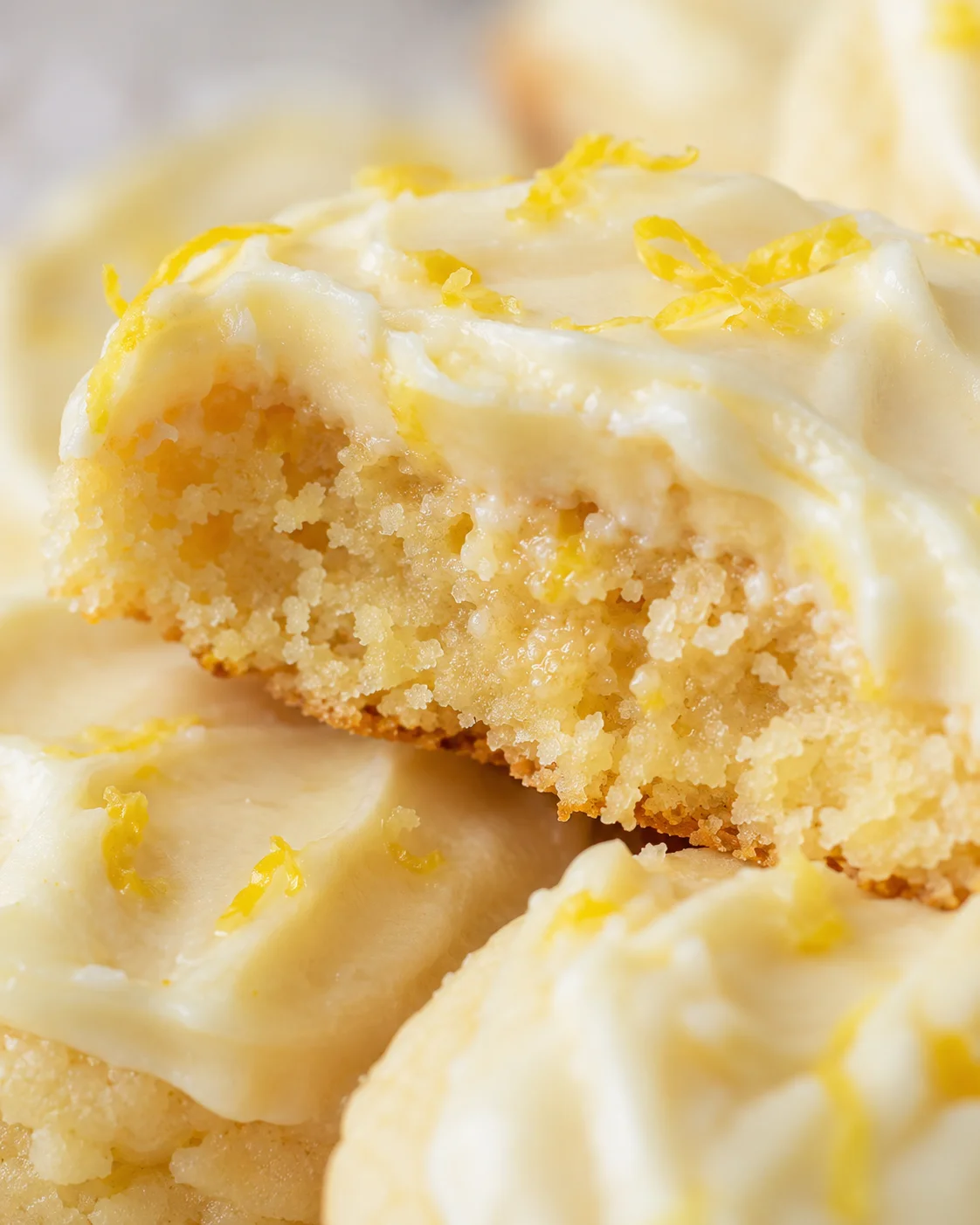 Close-up of soft lemon cookies with creamy lemon frosting and zest topping.