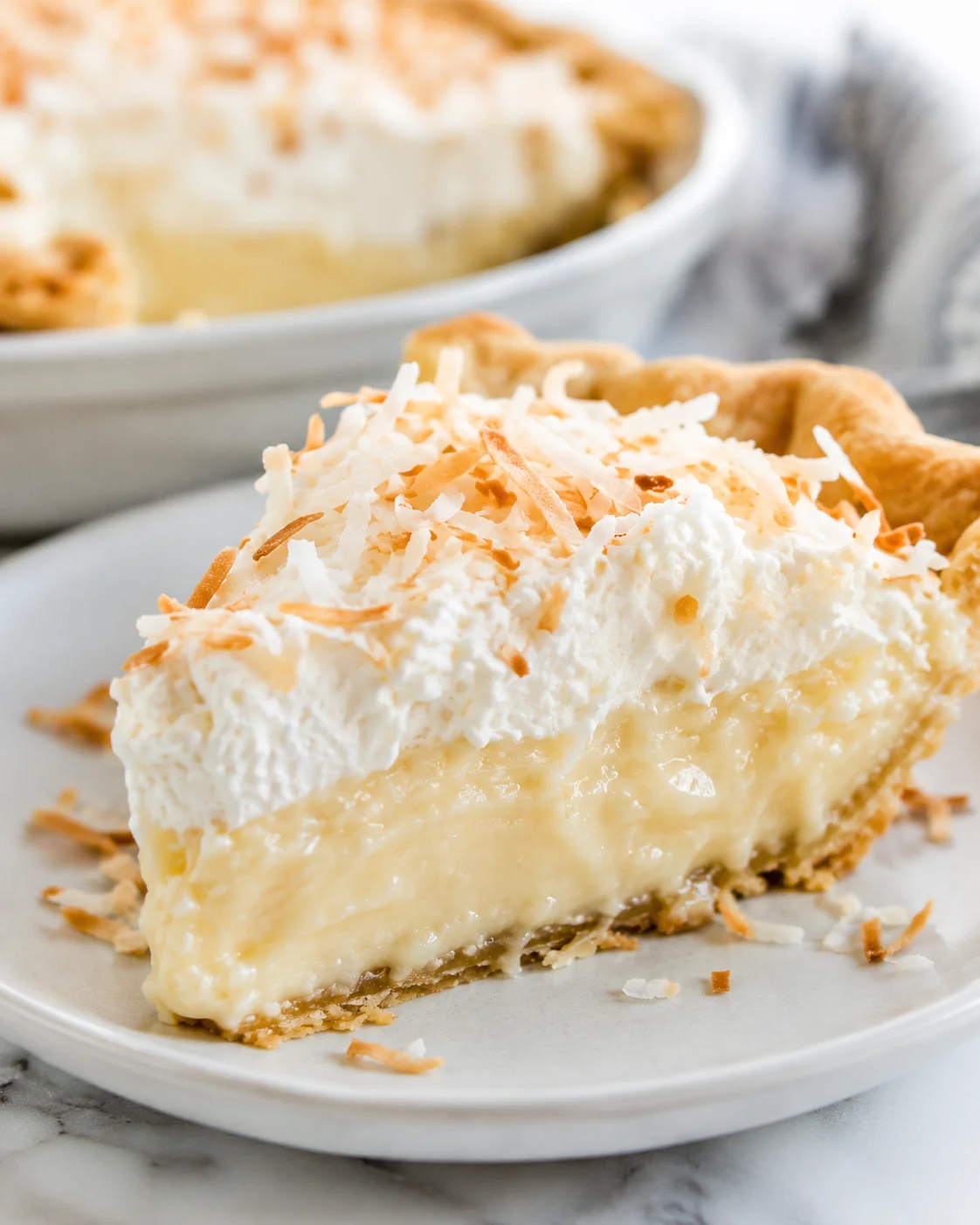 Creamy coconut cream pie topped with toasted coconut flakes and whipped cream