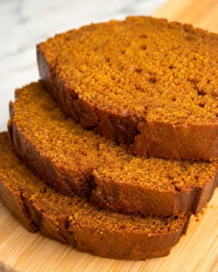 Close-up of moist, spiced pumpkin bread slices on a wooden surface.