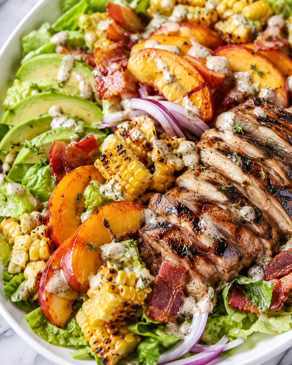 Colorful salad with grilled rosemary chicken, peaches, bacon, and charred corn