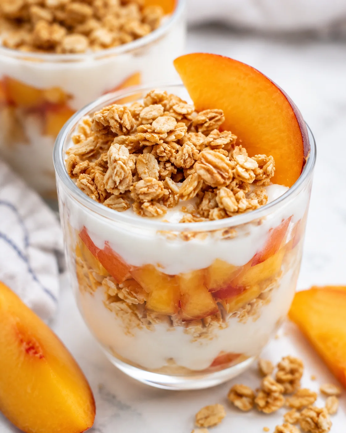 Delicious layered parfait with fresh peaches, yogurt, and crunchy granola