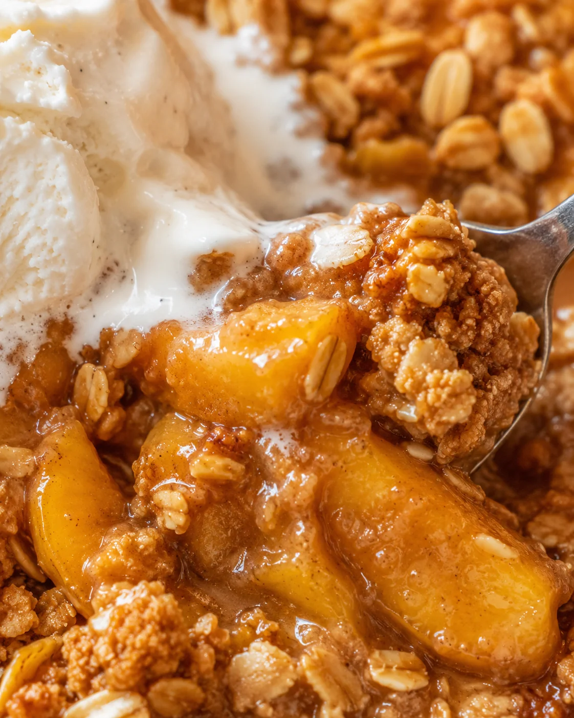 Close-up of warm peach crisp served with vanilla ice cream.