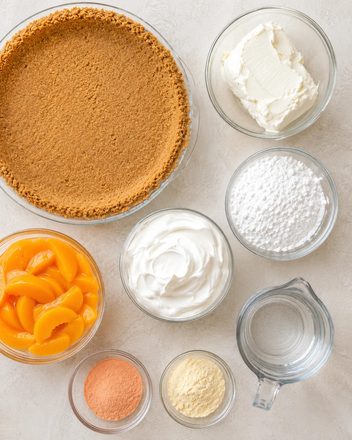 Ingredients for creamy peach pie including graham cracker crust, cream cheese, peaches, pudding, and gelatin.