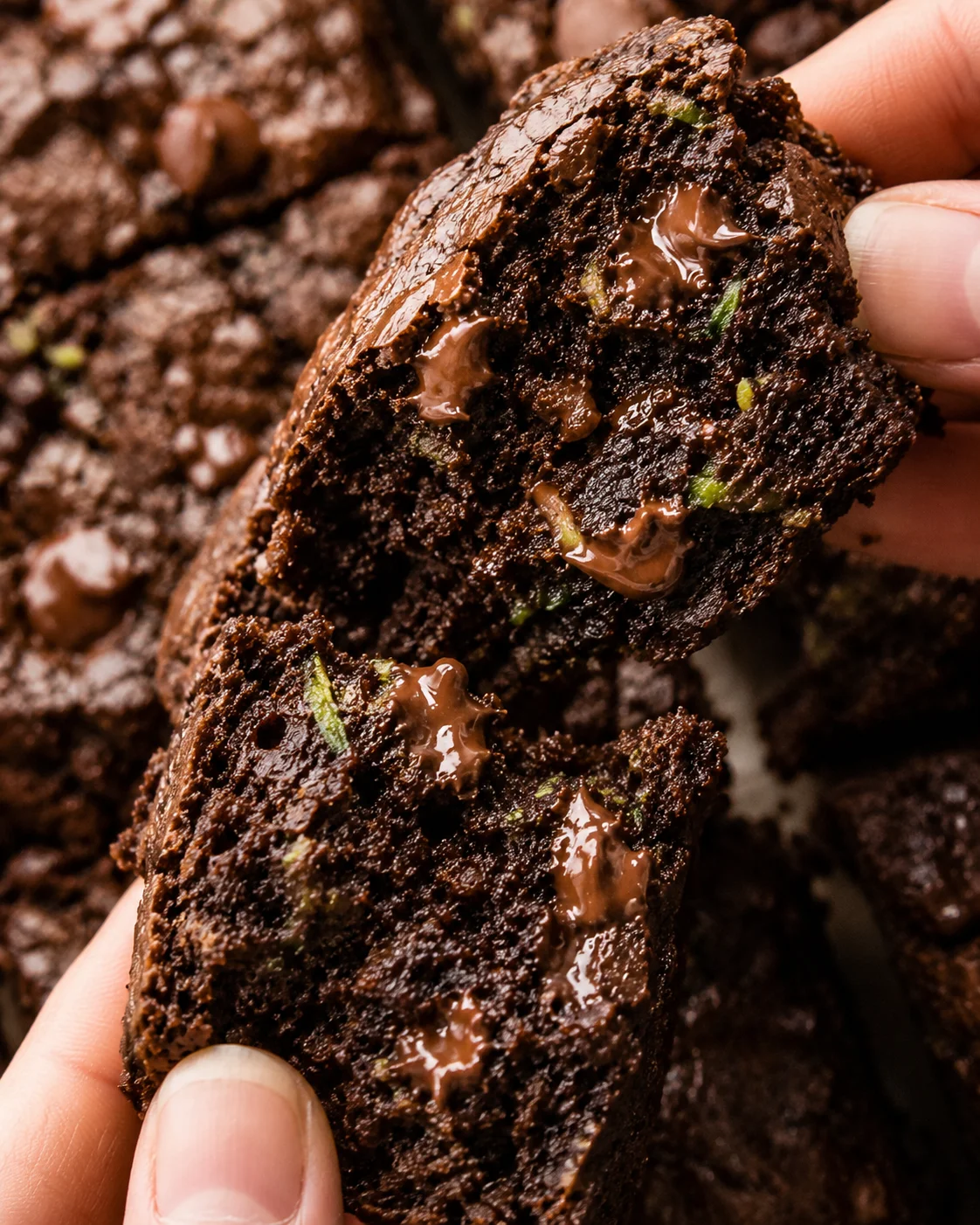 Close-up of fudgy zucchini brownies with melted chocolate and green zucchini bits