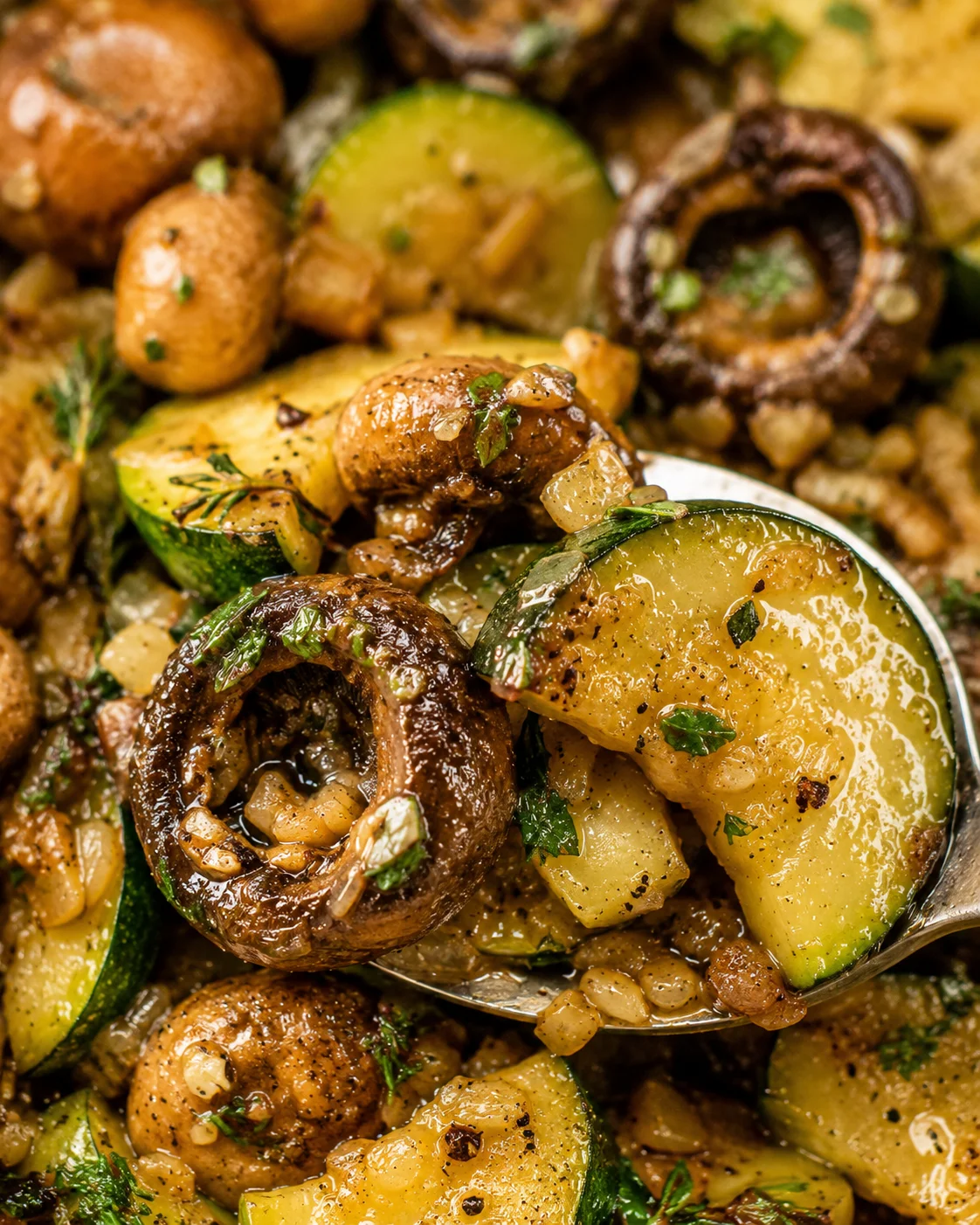 Close-up of sautéed zucchini and mushrooms in a skillet with herbs and garlic
