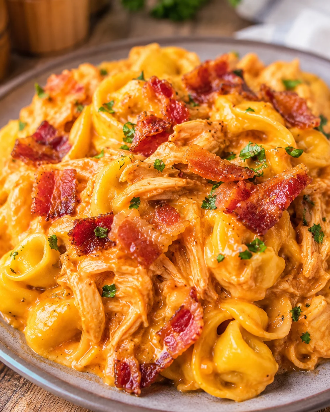 A close-up of cheesy BBQ bacon chicken tortellini on a plate.