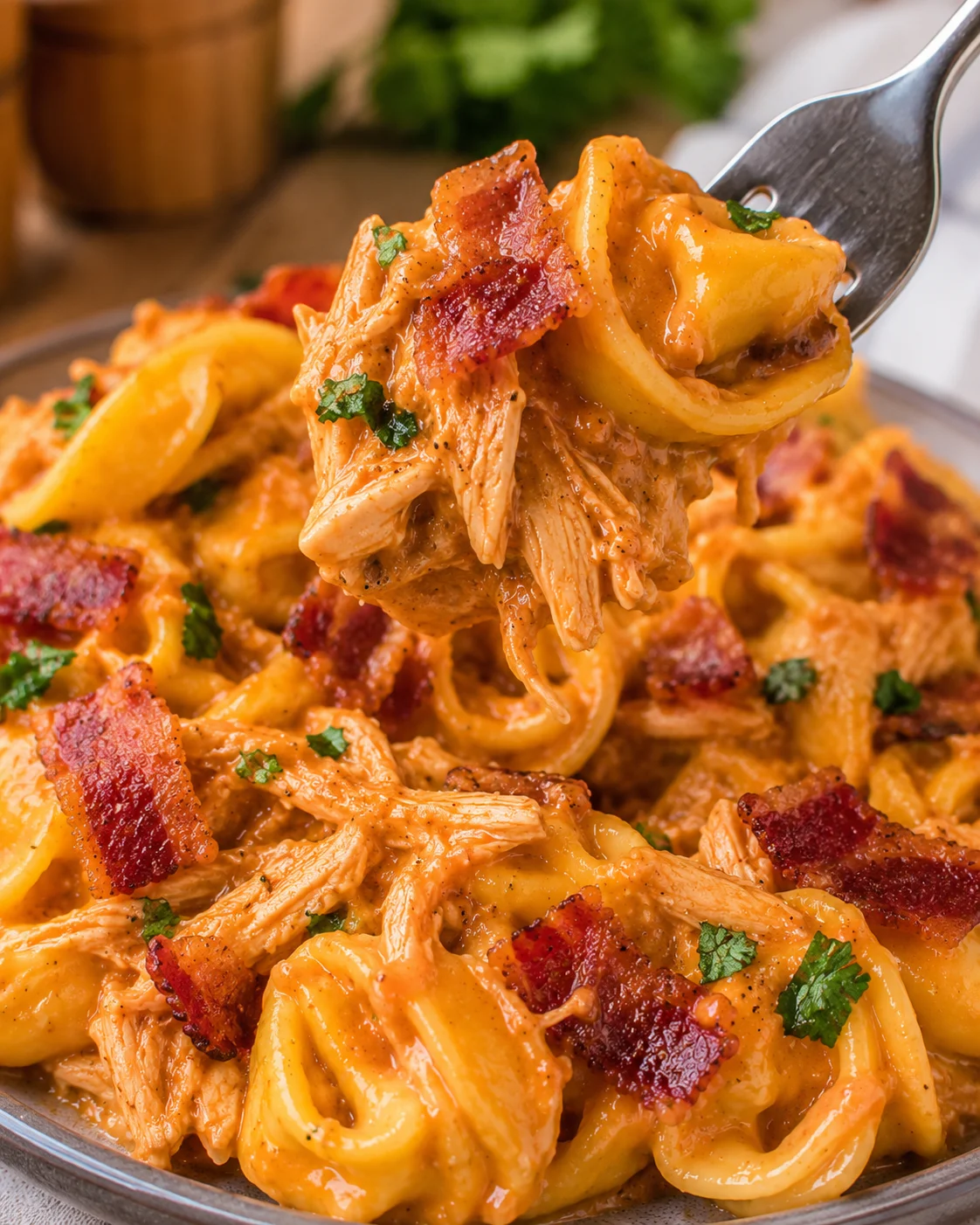 Close-up of cheesy BBQ bacon chicken tortellini being served on a plate.