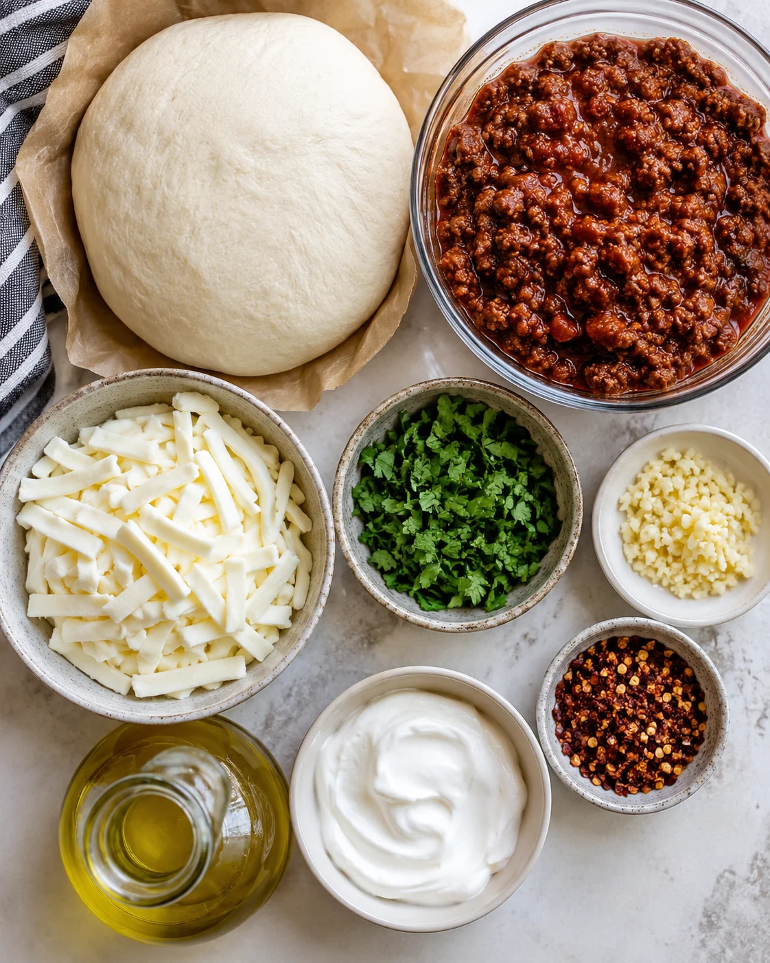 Photo of pizza dough, chili, cheeses, herbs, and spices for recipe preparation.