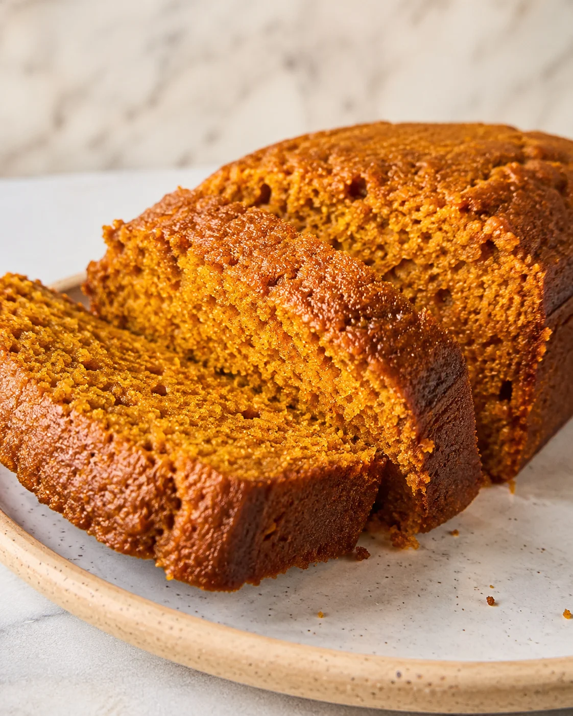 Moist, warmly spiced pumpkin bread with a golden-brown crust on a plate.