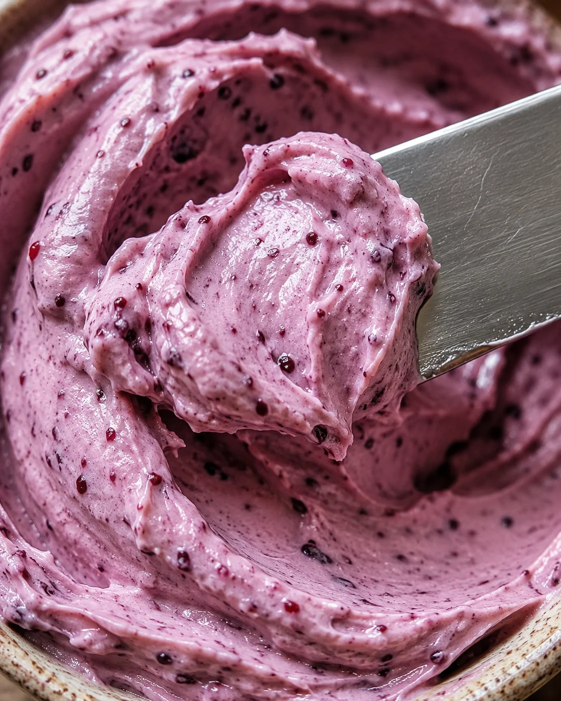 Creamy blackberry compound butter with seeds removed, shown in a bowl with a spatula.