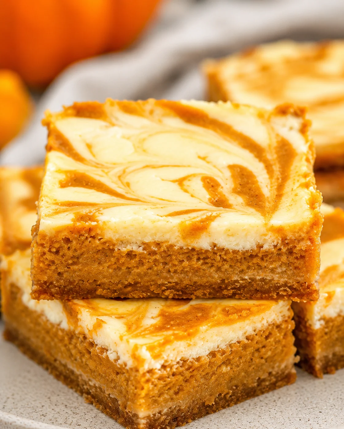 Delicious pumpkin cheesecake bars with a marbled swirl topping, perfect for fall desserts.