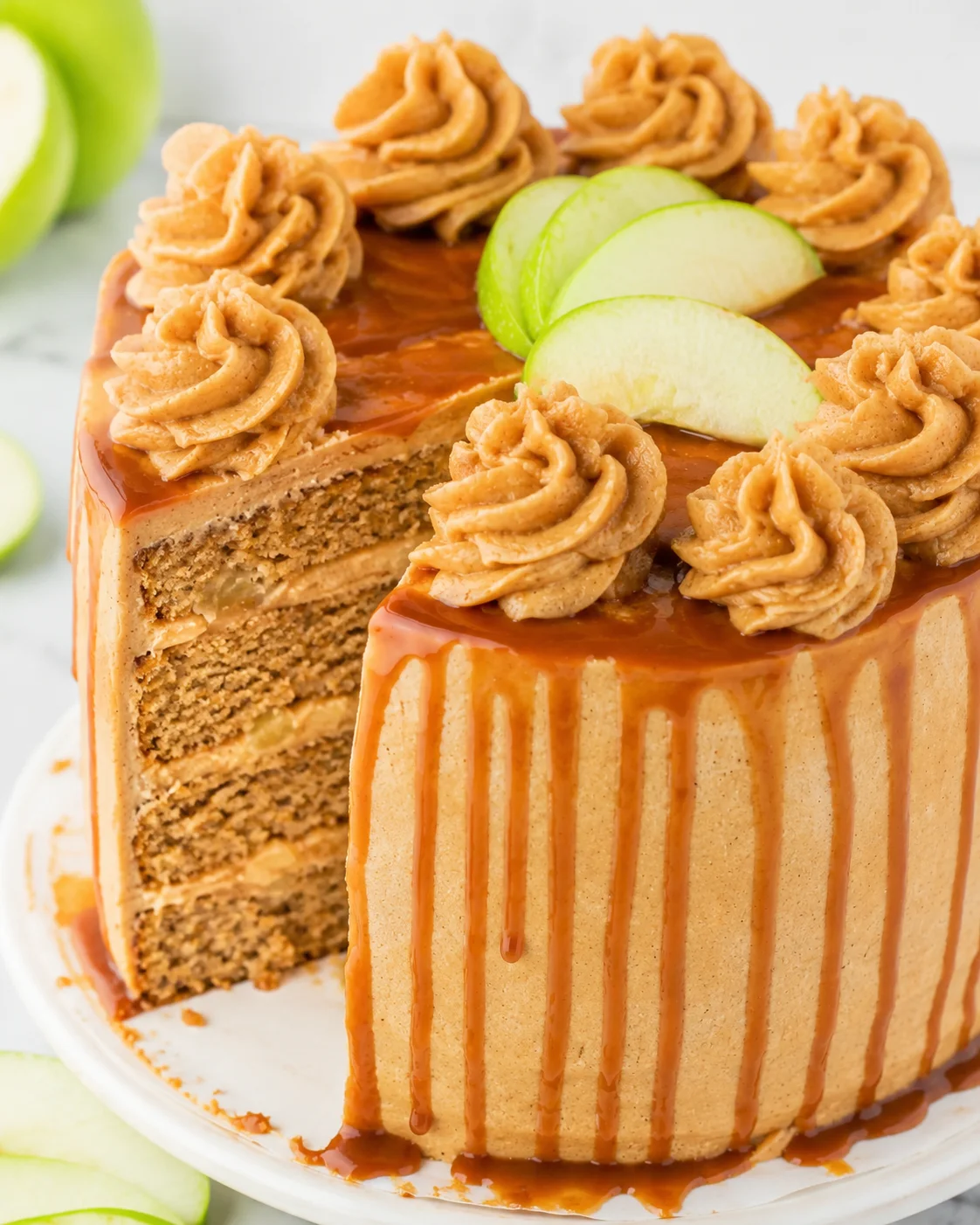 Delicious caramel apple spice cake topped with piped frosting and apple slices.