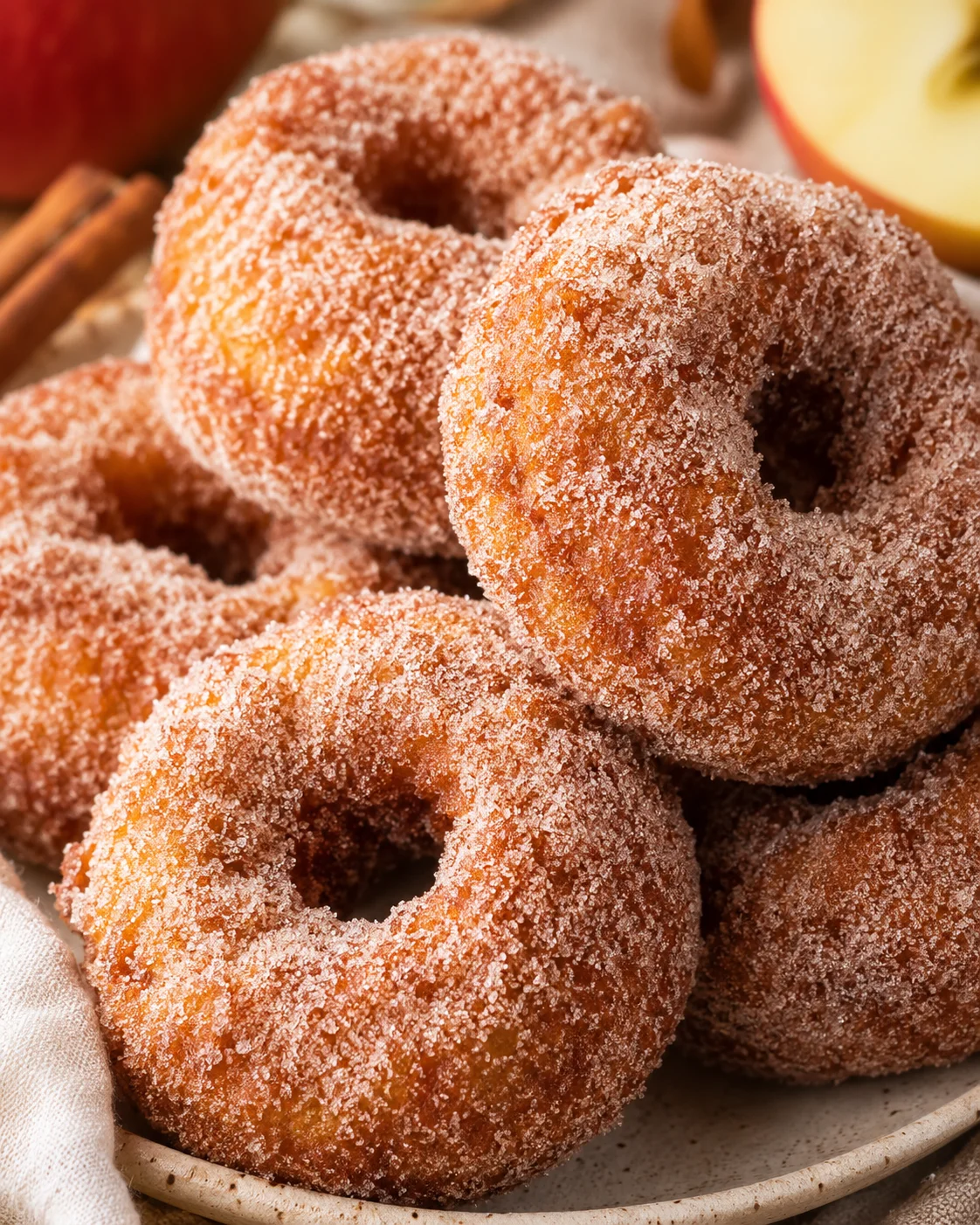 Close-up of golden fried apple cider donuts coated with cinnamon sugar.