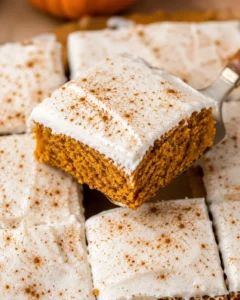 Close-up of moist pumpkin bars topped with a creamy frosting and sprinkled with spices