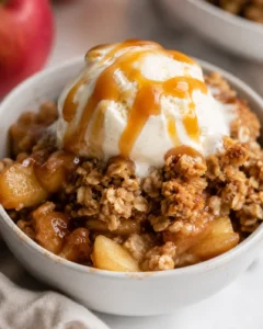 Delicious gluten-free apple crisp topped with ice cream and caramel sauce.