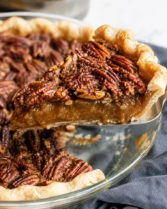 A slice of pecan pie being lifted on a spatula showing the gooey interior and pecan topping