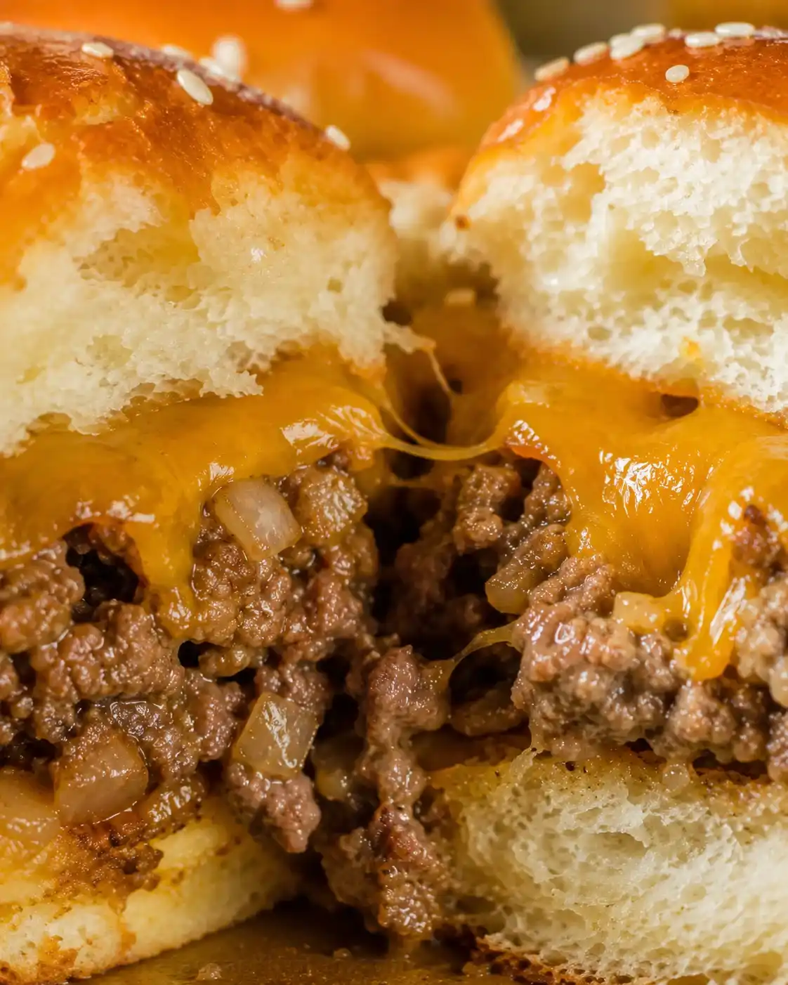 Interior close-up of cheeseburger sliders showing melted cheese pull and beef filling
