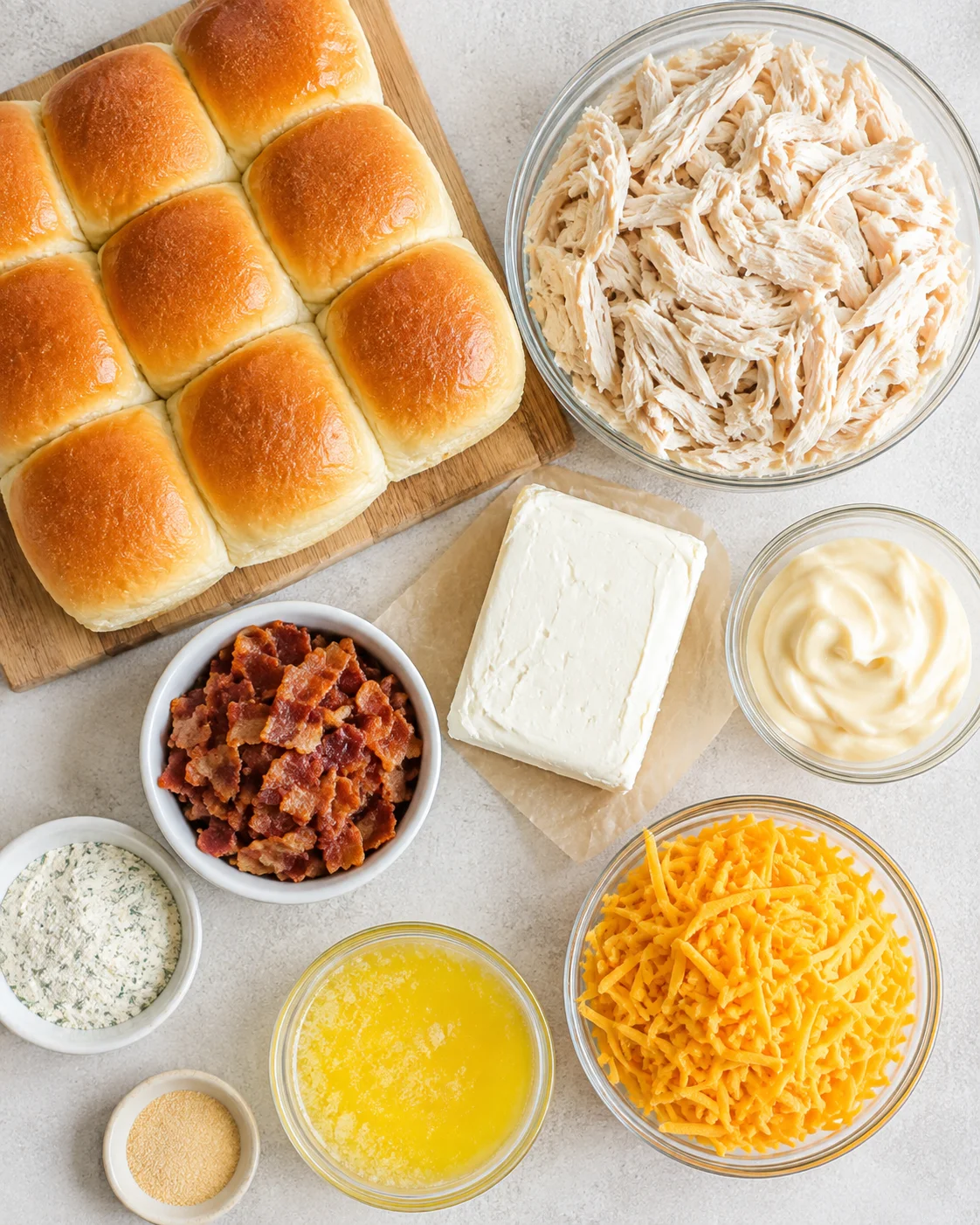 Top-down view of ingredients for Chicken Bacon Ranch Sliders including rolls, shredded chicken, cream cheese, bacon and cheddar