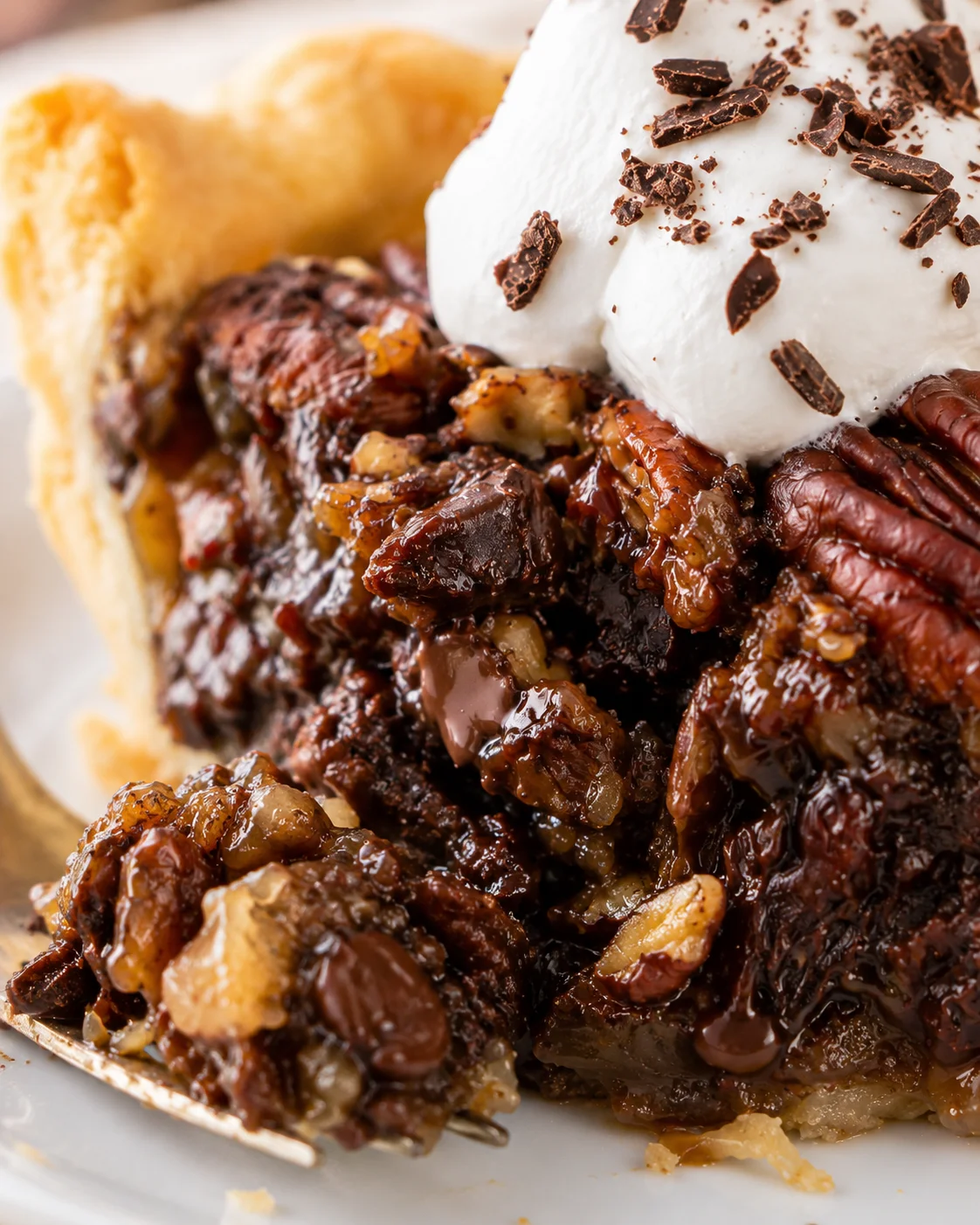 Close-up of the chocolate pecan pie interior showing gooey filling and pecans under whipped cream