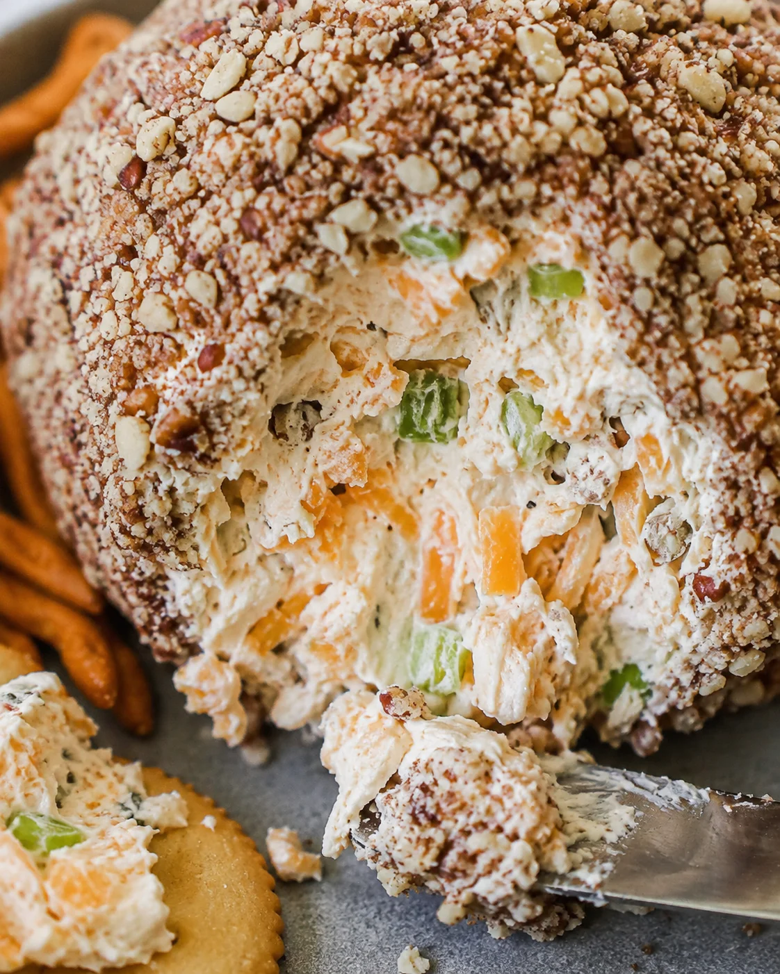Close detail of the classic cheese ball interior showing shredded cheddar, green onion, and pecan coating