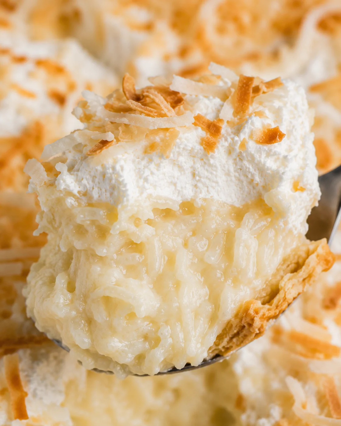 Close-up spoonful of coconut cream pie showing shredded coconut and creamy filling