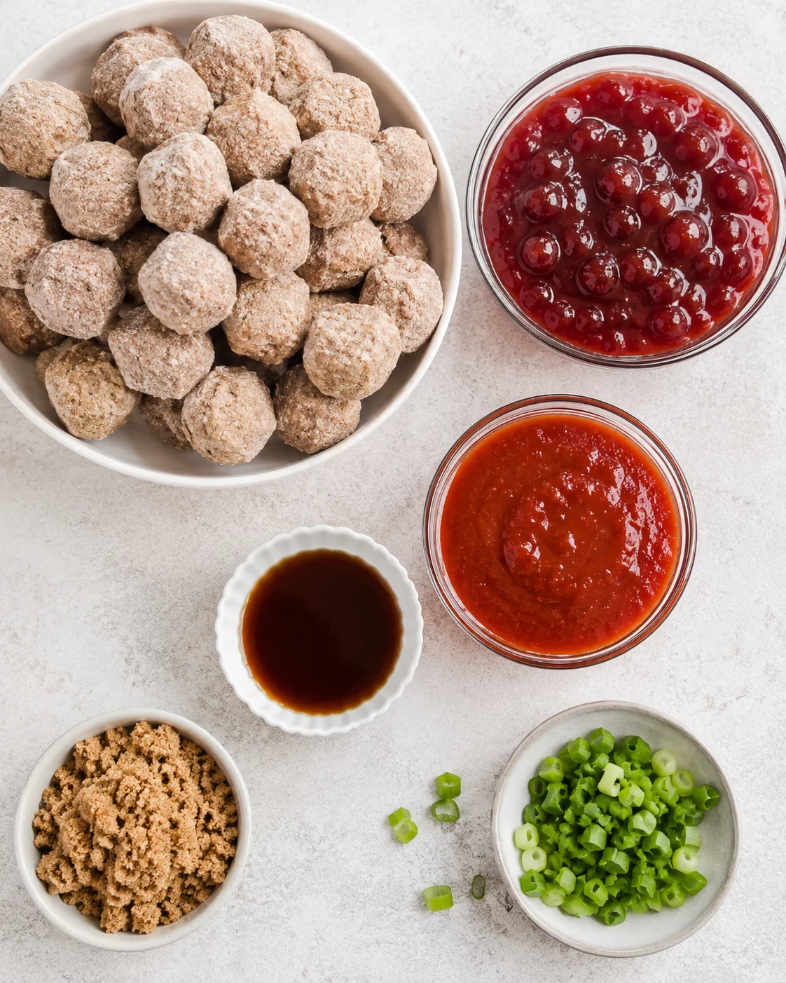 Top-down view of ingredients: frozen meatballs, whole cranberry sauce, chili sauce, brown sugar, Worcestershire and chopped green onions