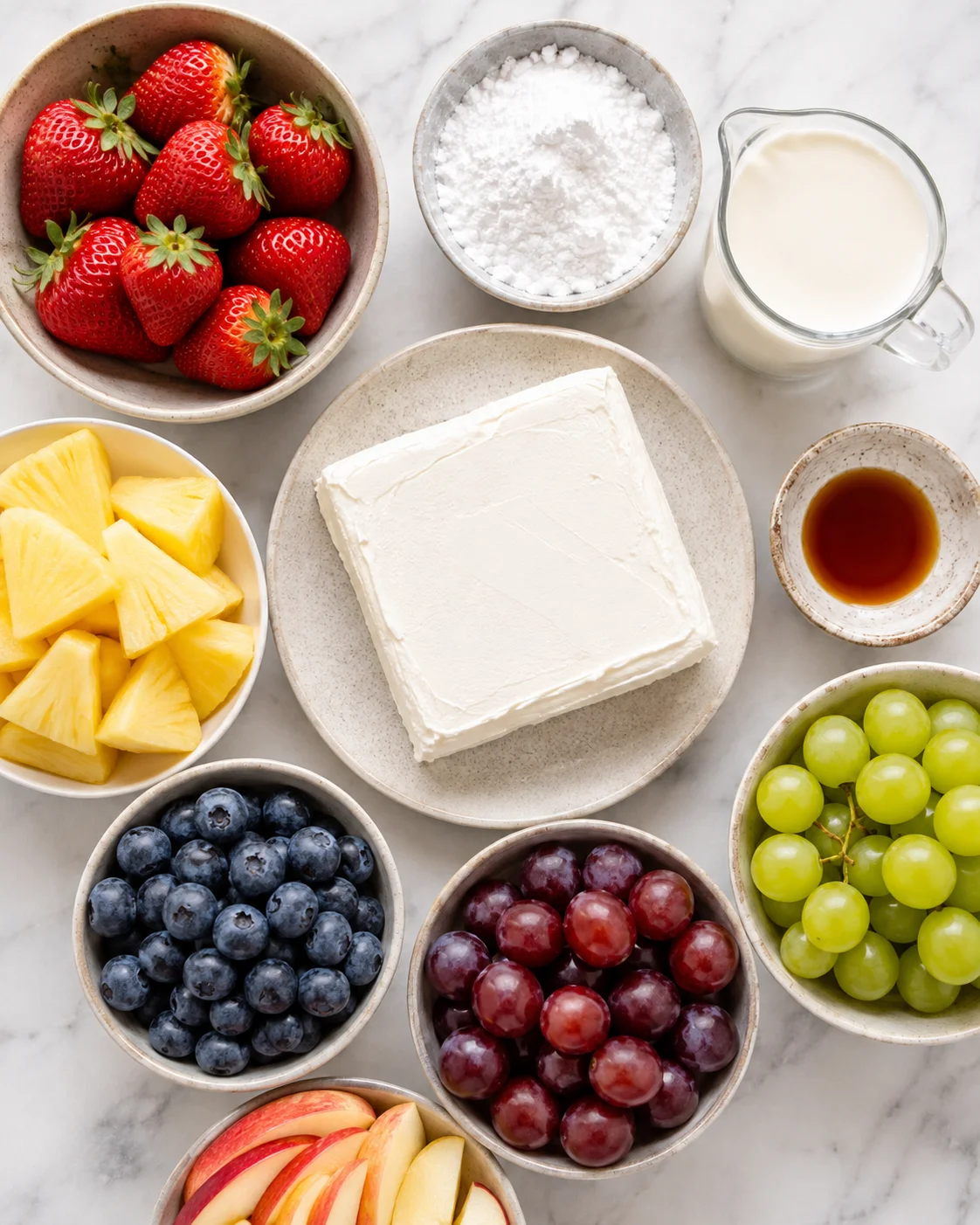Top-down of ingredients for cream cheese fruit dip including cream cheese, powdered sugar and heavy cream