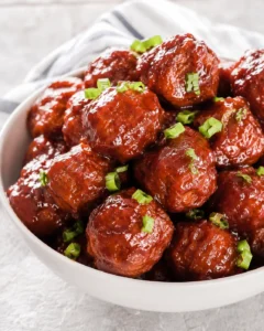 Bowl of cranberry-glazed crockpot meatballs garnished with chopped green onions