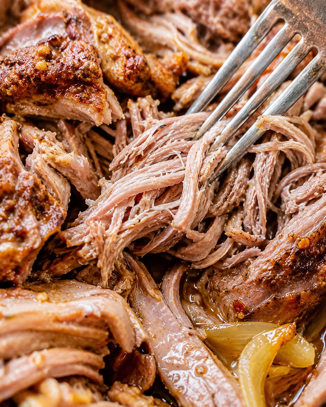 Fork pulling shredded strands of crockpot pork roast