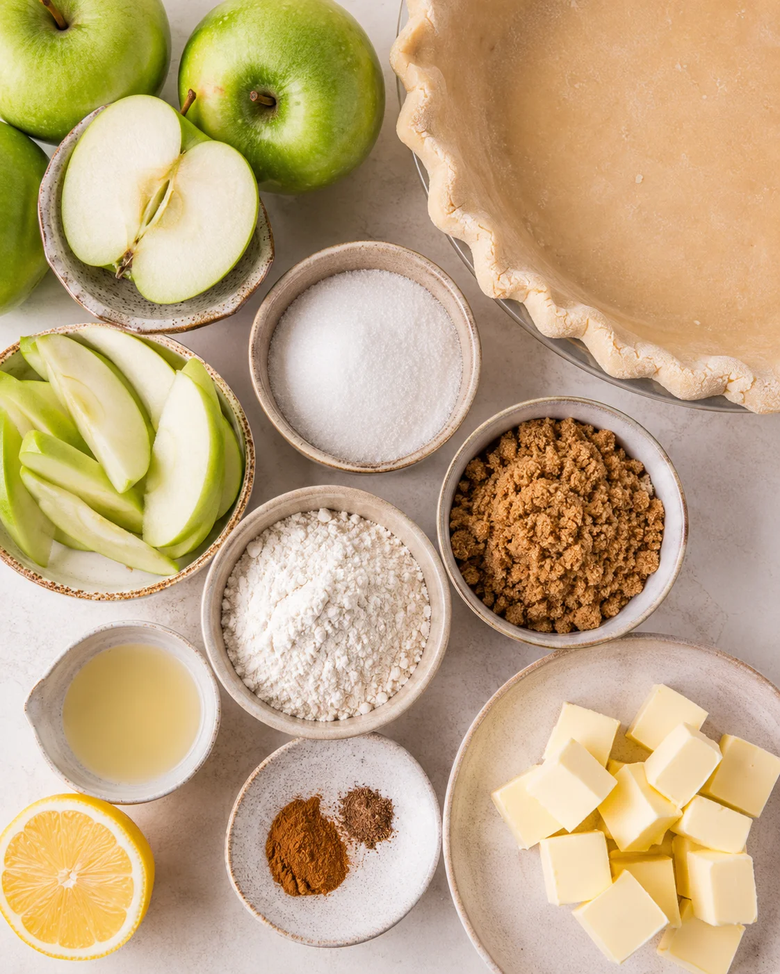 Top-down array of Dutch apple pie ingredients including apples, flour, sugars, butter, spices and a pie crust