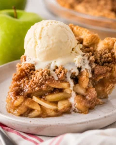 Slice of Dutch apple pie topped with a scoop of melting vanilla ice cream