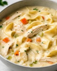 Bowl of easy creamy chicken noodle soup with egg noodles, shredded chicken, carrots and celery