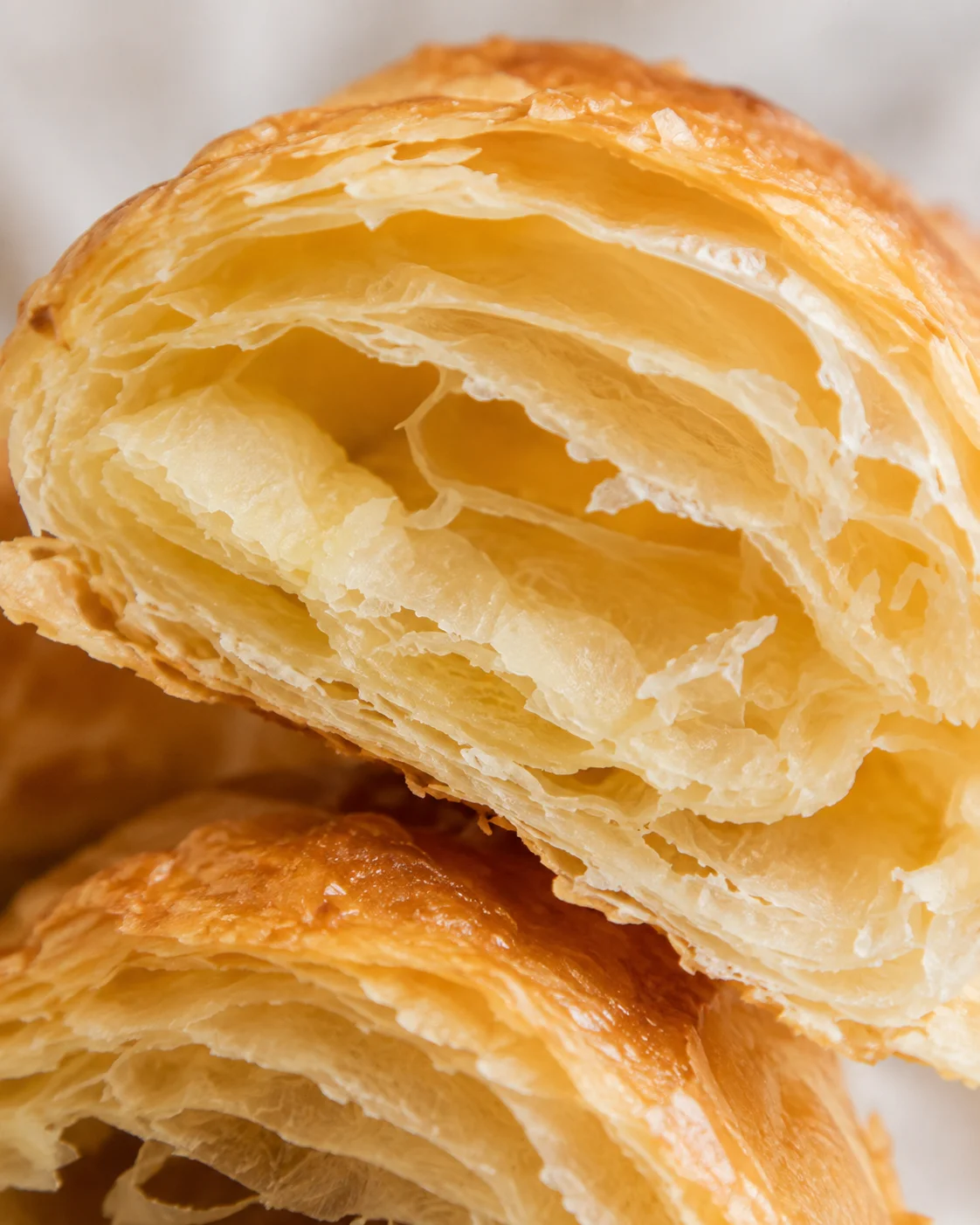 Close-up of baked puff pastry showing flaky golden layers from a croissant made with homemade puff pastry.