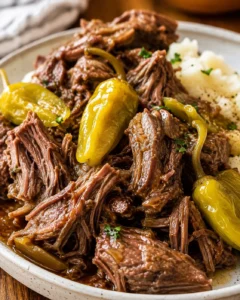 Shredded Instant Pot Mississippi pot roast with pepperoncini and mashed potatoes on a plate