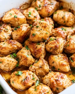 Glazed juicy oven baked chicken bites garnished with parsley in a baking dish