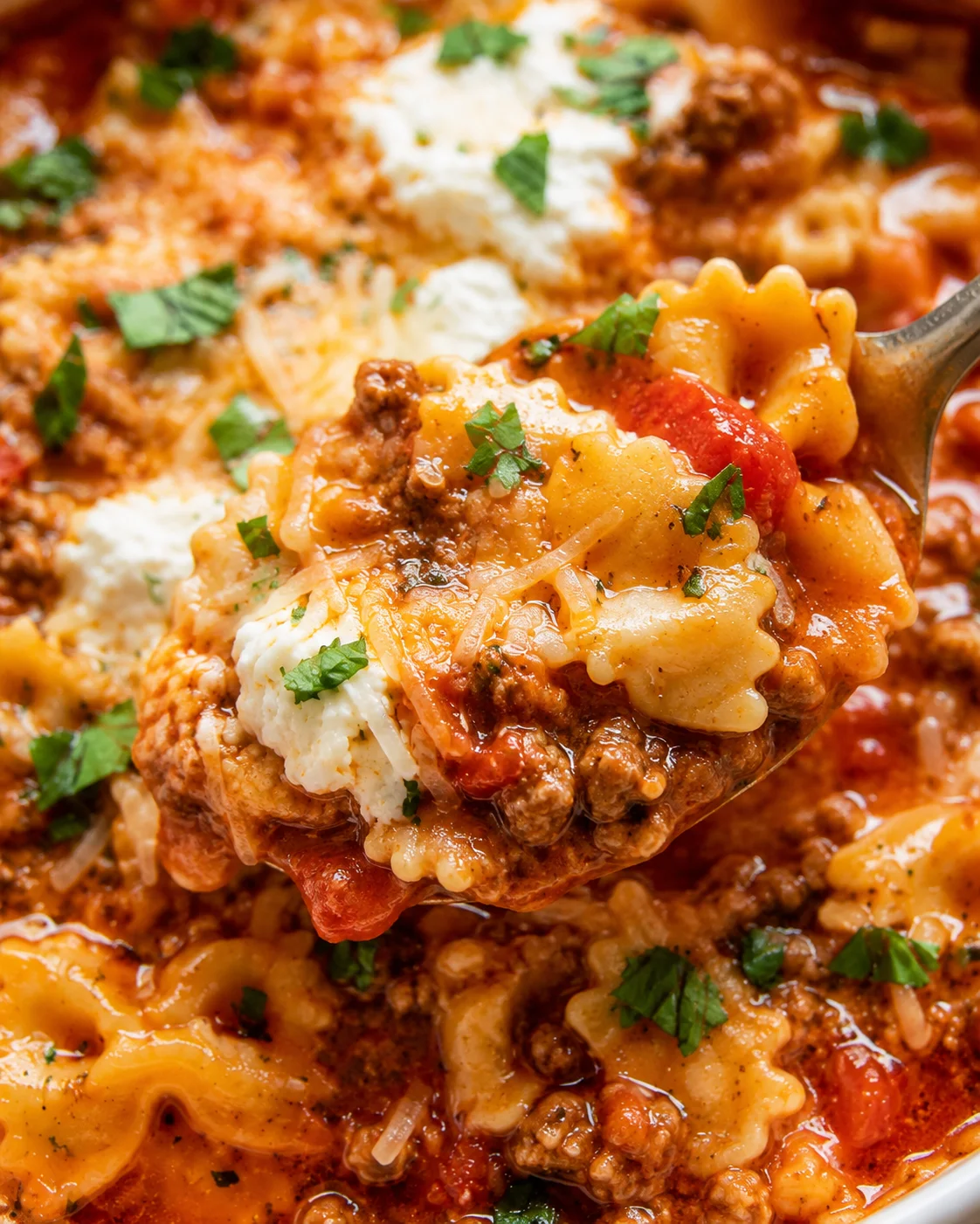 Close-up detail of a spoonful showing pasta, ground beef, sauce and ricotta in lasagna soup