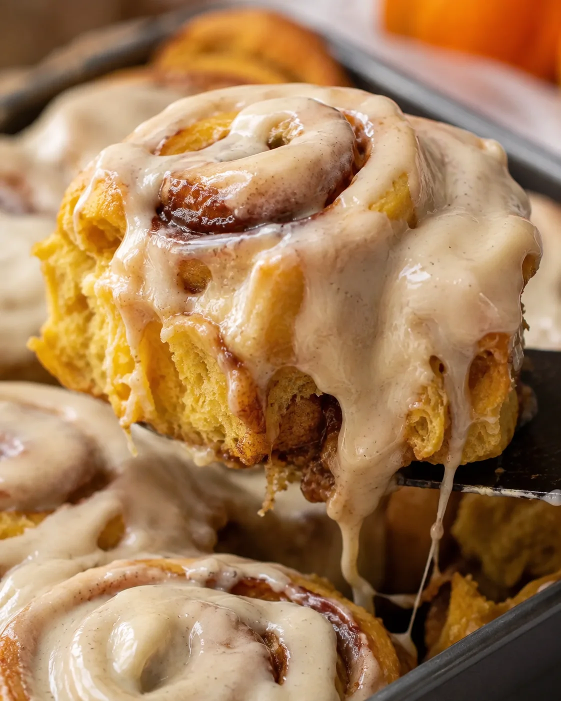 Close-up of soft pumpkin cinnamon rolls topped with creamy vanilla maple frosting.