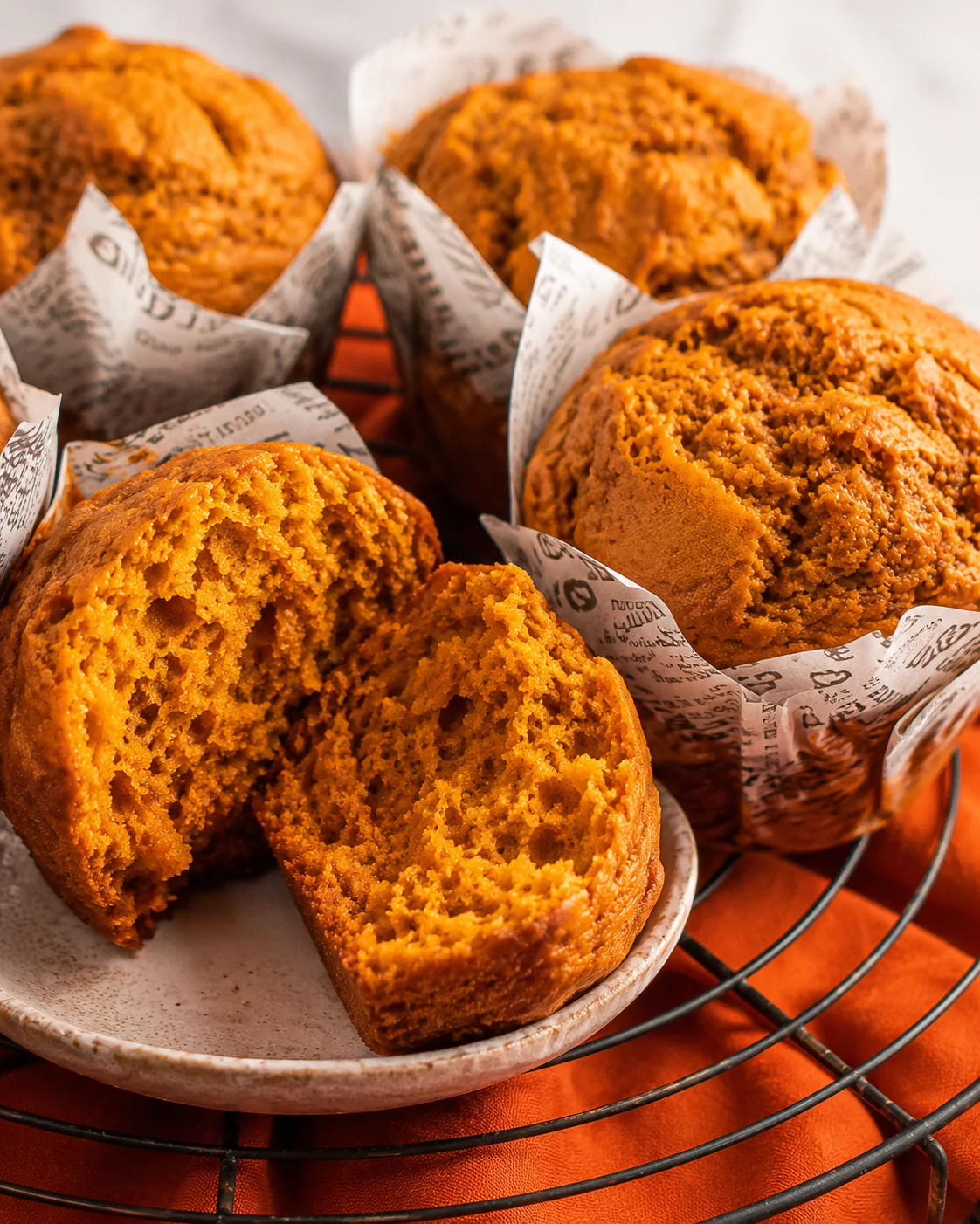 Bakery-style moist and fluffy pumpkin muffins with warm autumn spices on a wire rack.