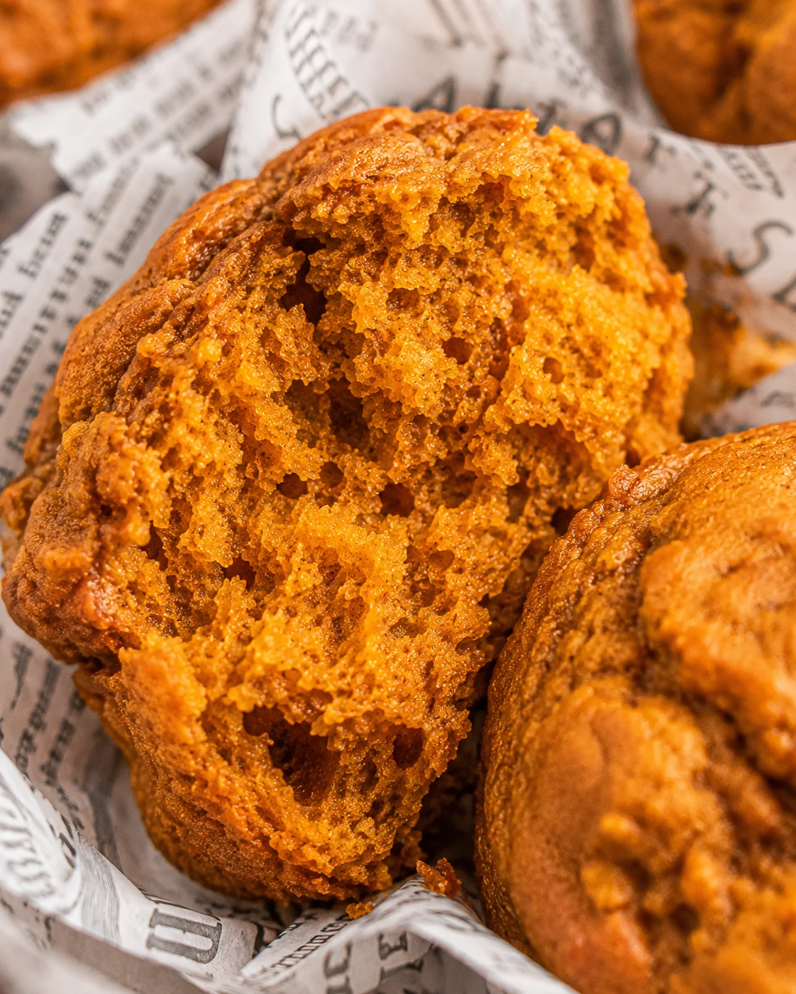Close-up of a soft, moist pumpkin muffin broken in half showing fluffy interior