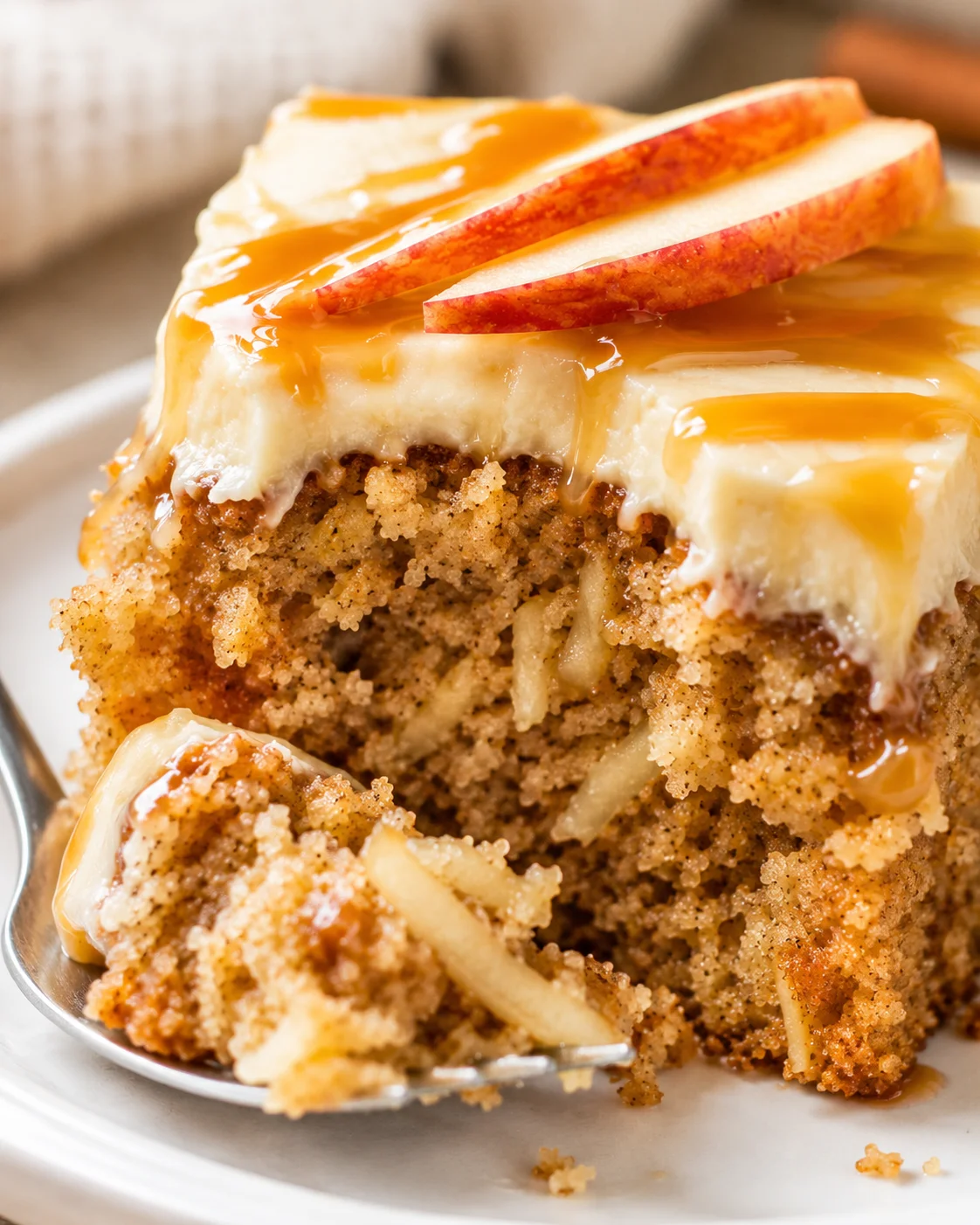 Slice of moist apple cake with caramel frosting and apple slices on top