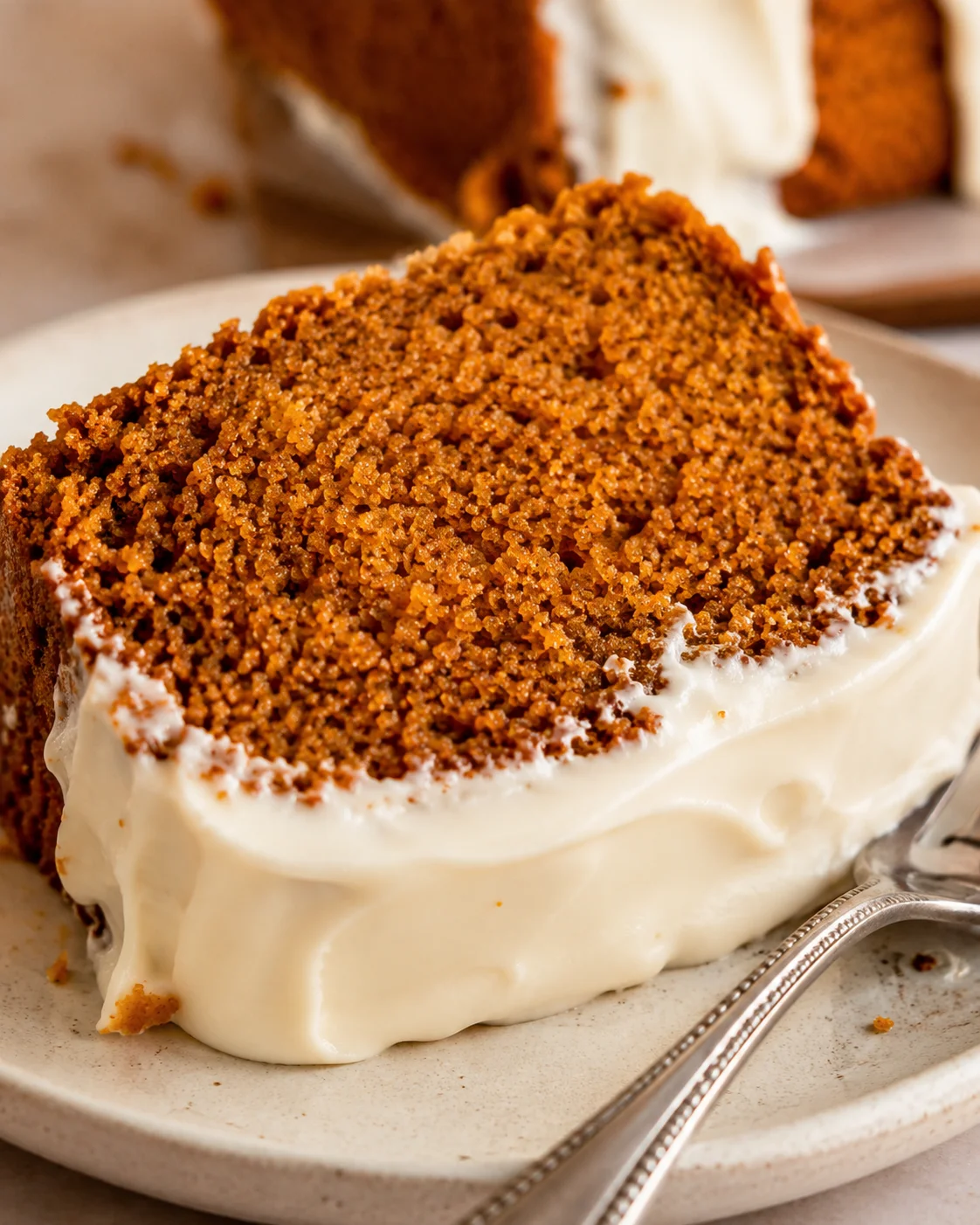 A slice of moist pumpkin bread topped with creamy, tangy cream cheese frosting.