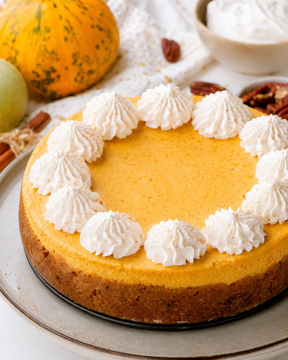 Creamy keto pumpkin cheesecake with a graham cracker-style nut crust and whipped topping.