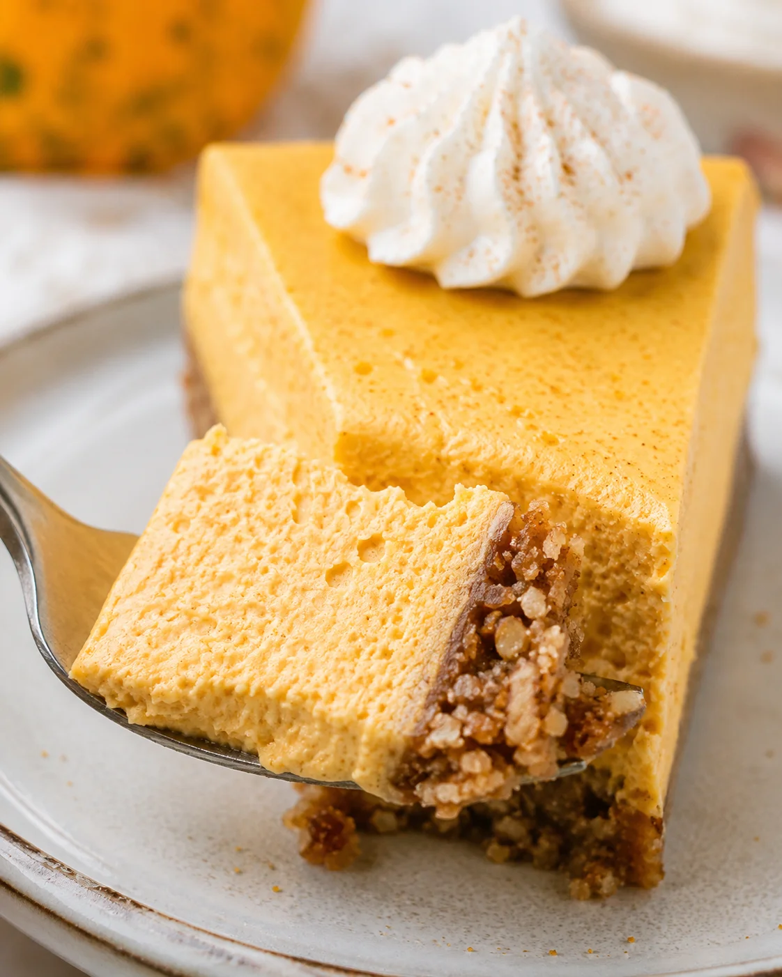 Creamy keto pumpkin cheesecake topped with whipped cream and spices.