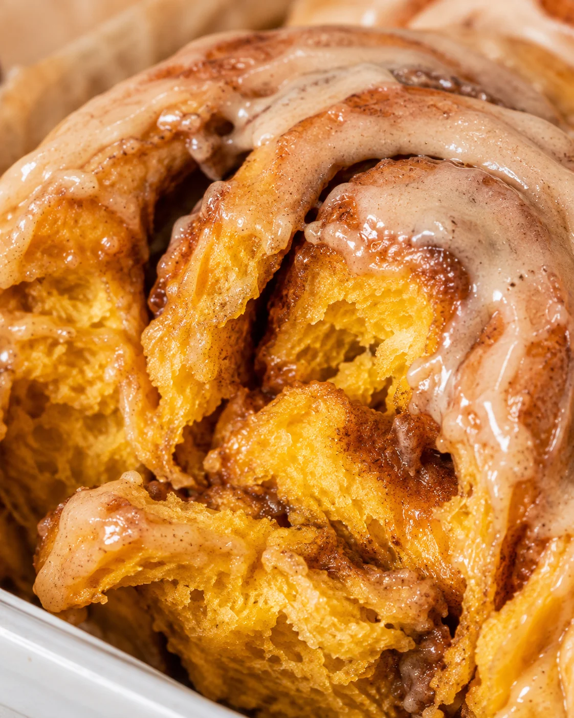 Close-up of freshly baked pumpkin cinnamon rolls with frosting drizzle